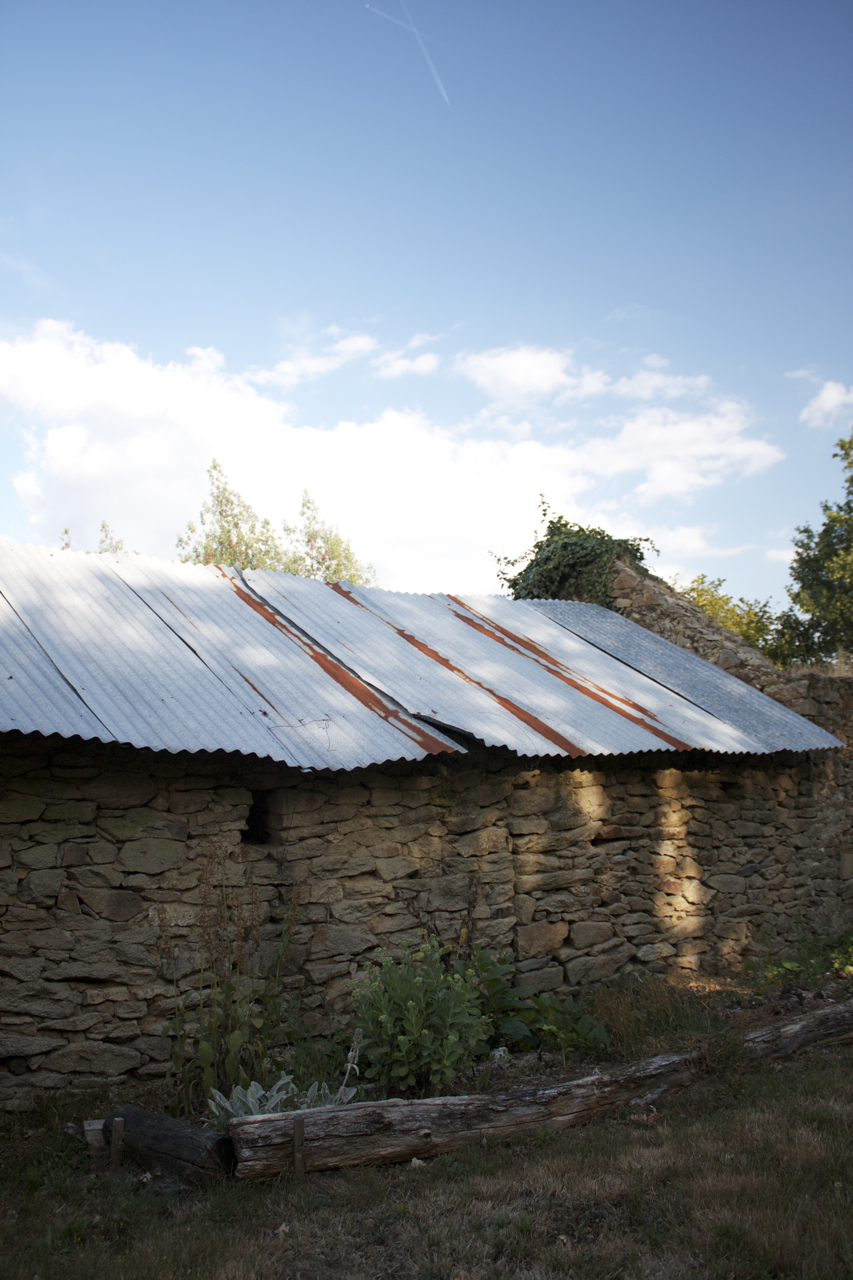 an old stone building with some metal on the roof