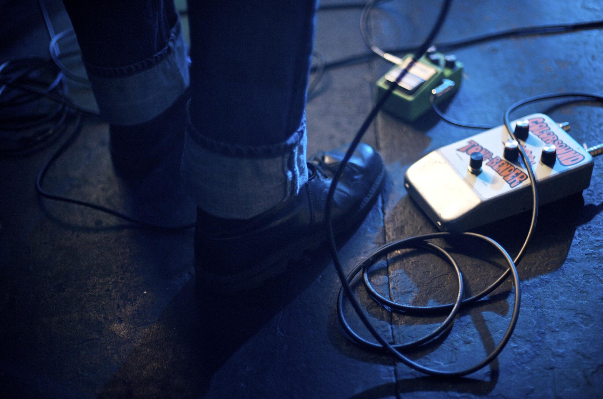 a person holding their foot while a guitar pedal is plugged into a charger