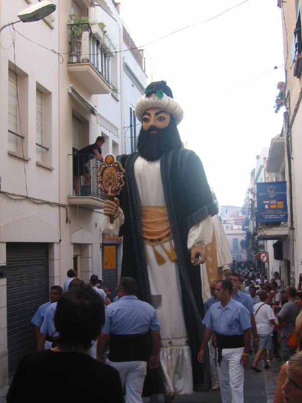 an elaborately decorated giant masked figure on a city street