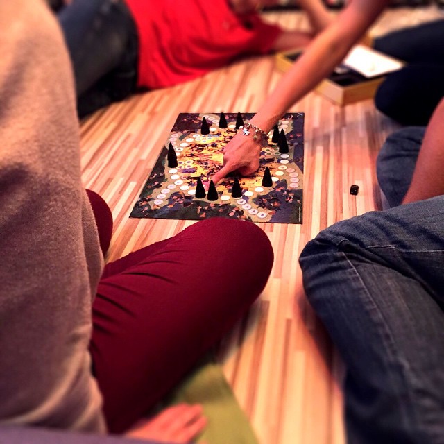 a group of people are sitting around a board game