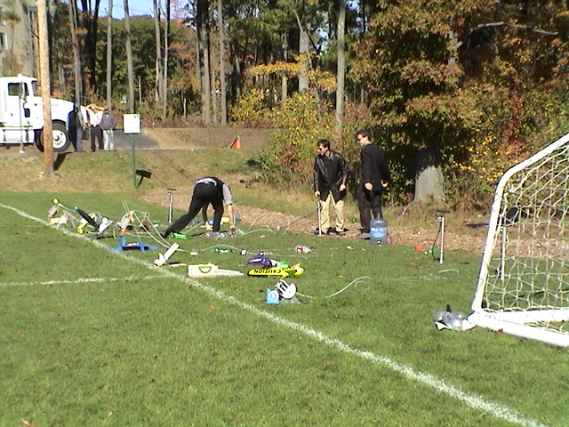 a soccer goalie in a green field next to some soccer equipment