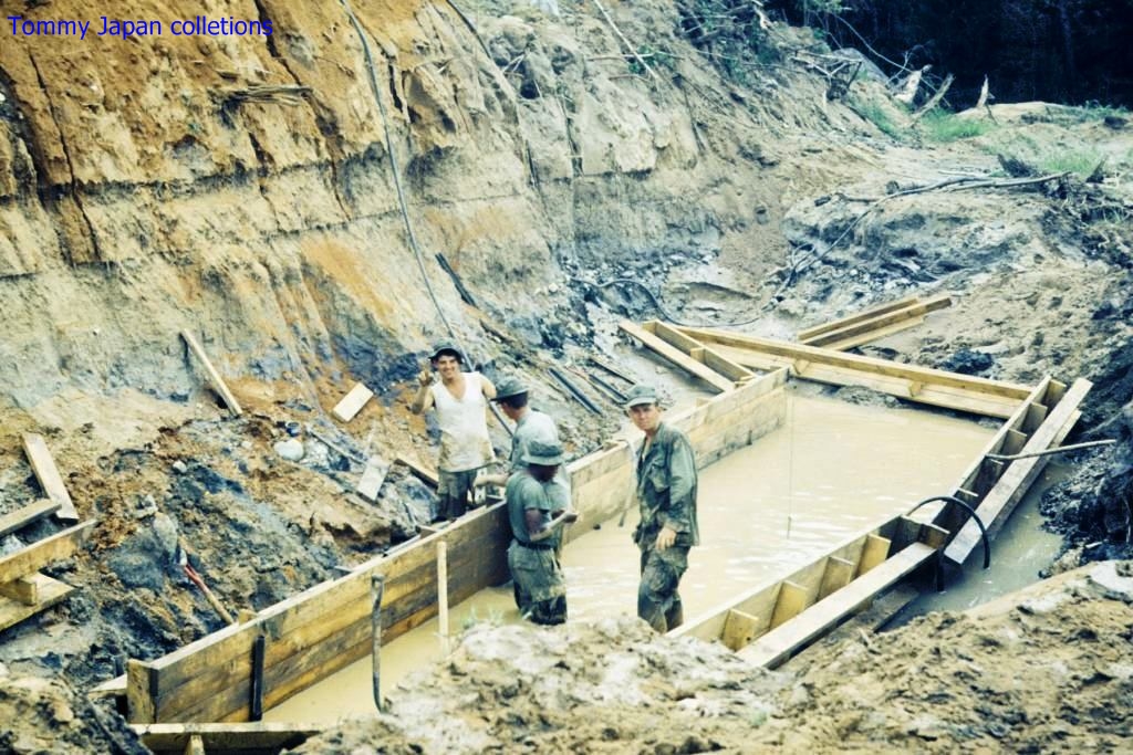 men with guns stand in muddy water at a construction site