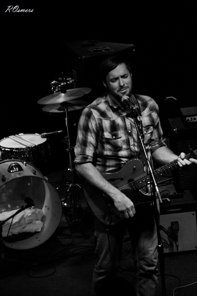 a man with a guitar playing drums on stage