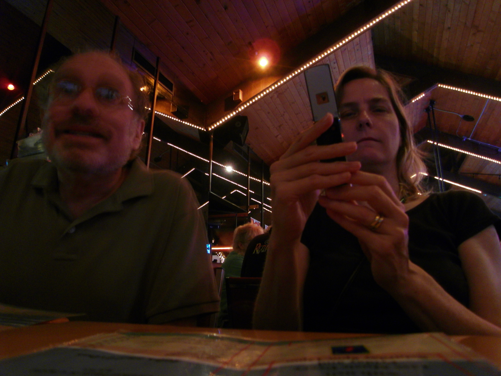 man and woman on cellphones in a bar