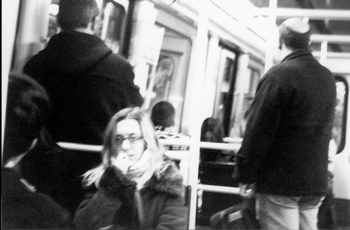 a black and white po shows people walking by in a subway car