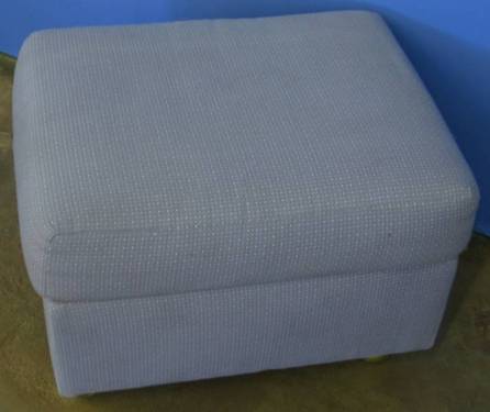 a white foot stool sitting next to a blue wall