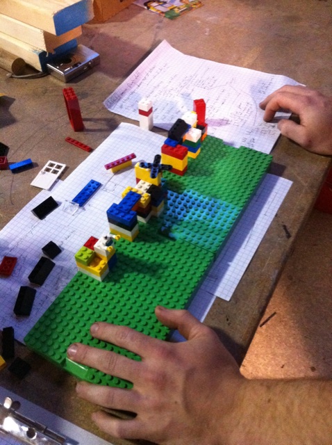 a person who is sitting at a table making a lego creation