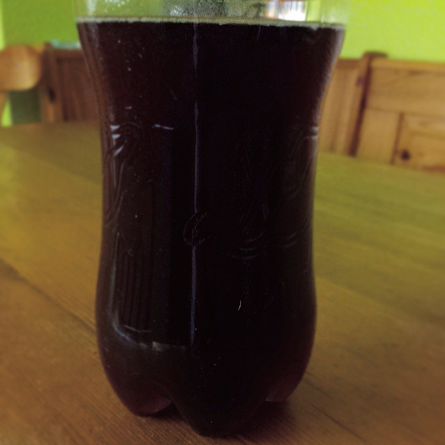 a brown glass with black liquid on top of a table