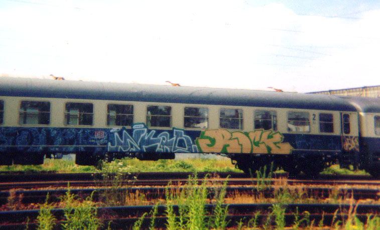 the train is parked in the tracks covered with graffiti