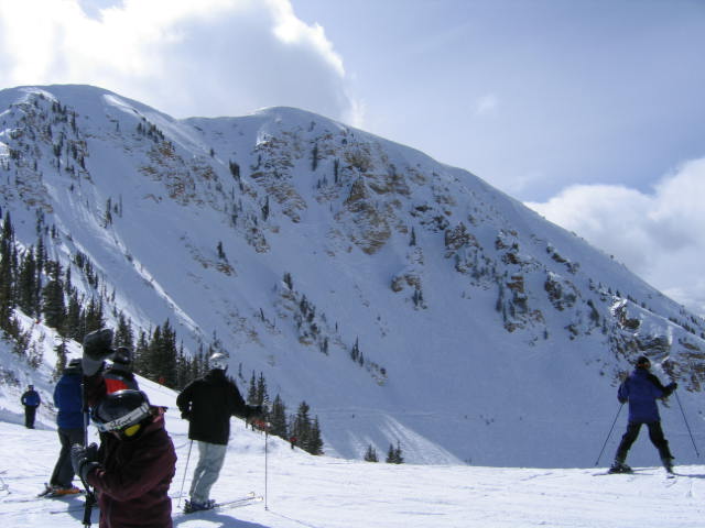 skiers on a snowy mountain slope near a large mountain