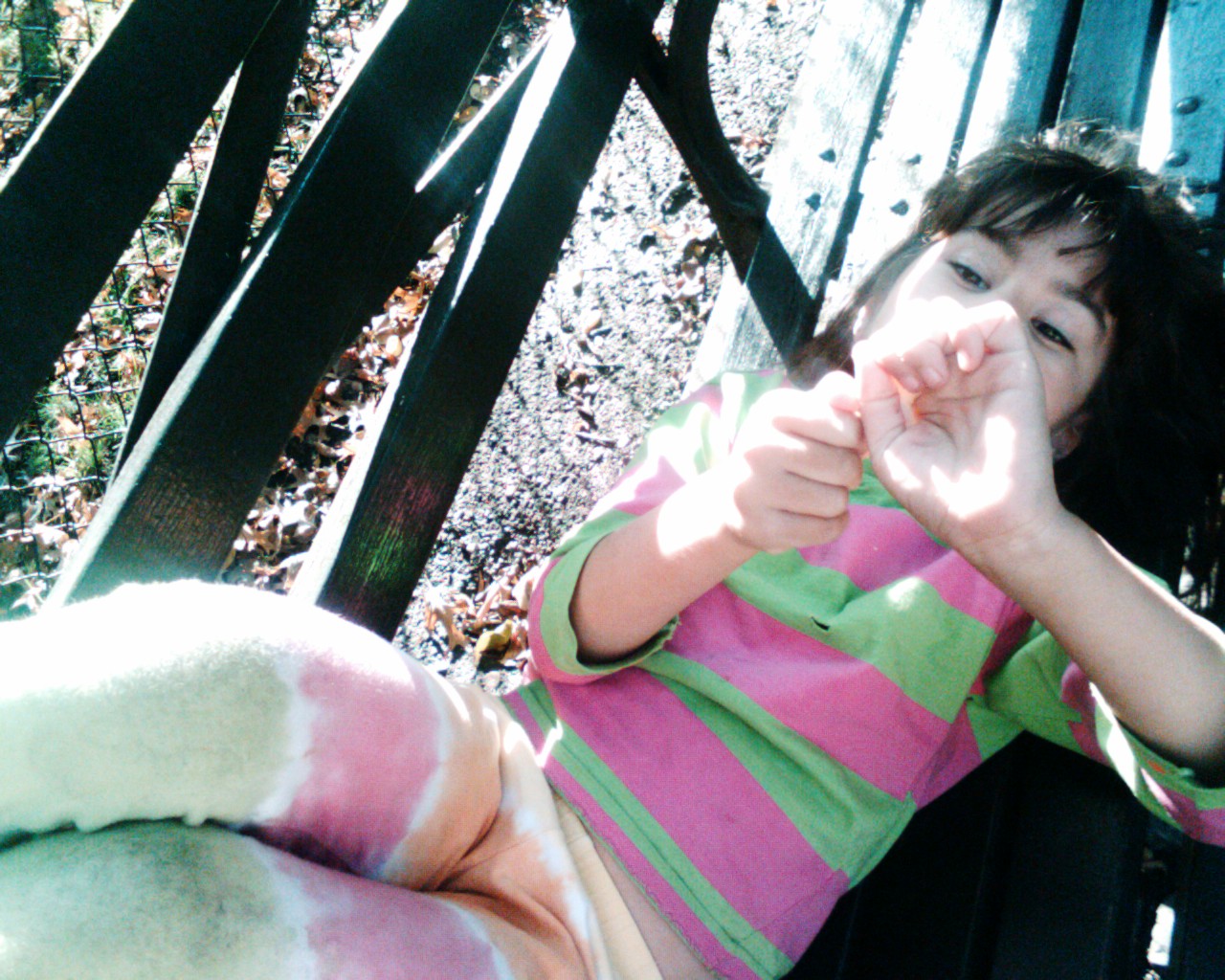 a little girl in green, pink and white dress on a park bench