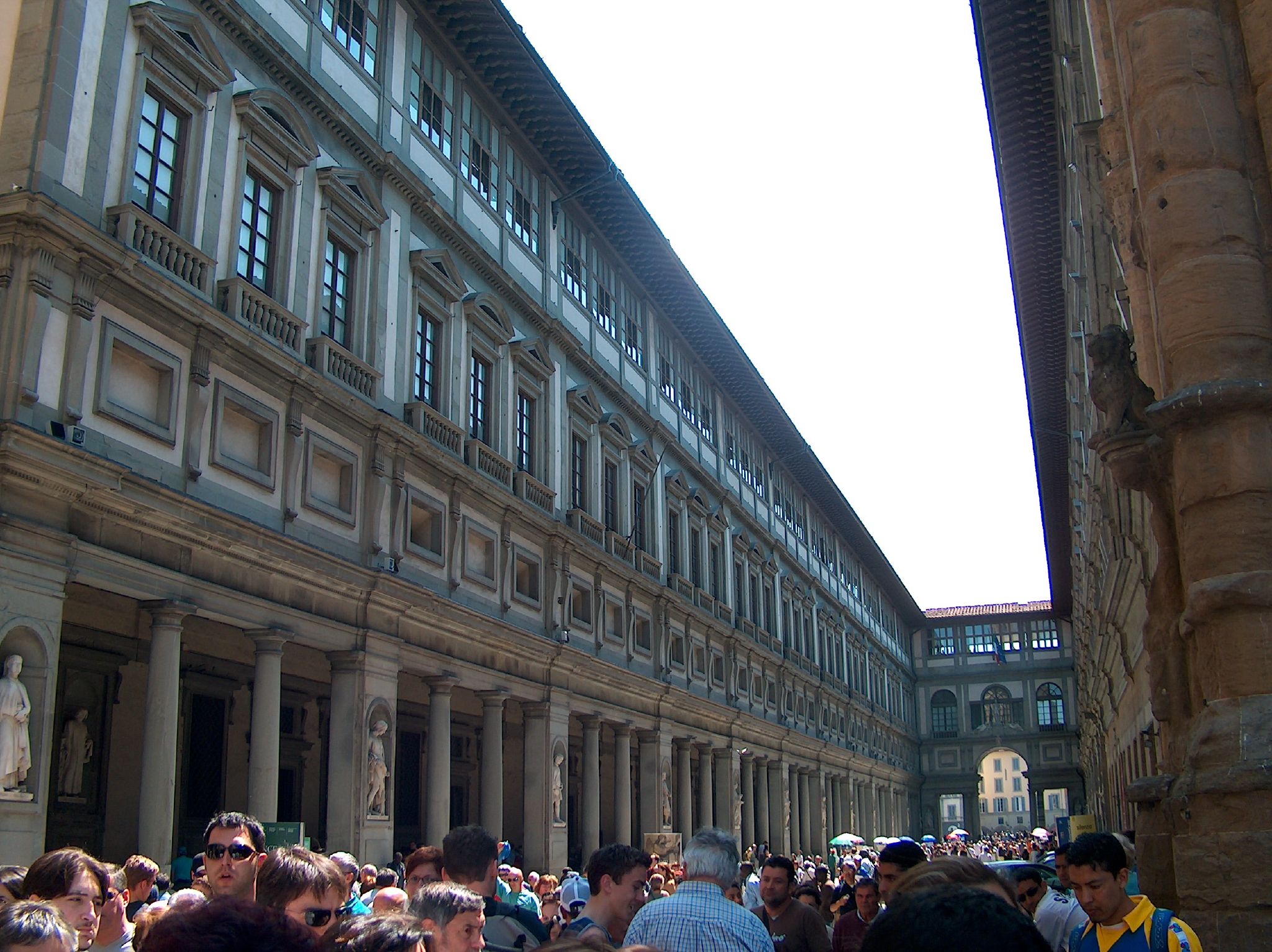 a crowd of people standing in front of large buildings