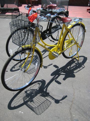two yellow bicycles are parked with baskets
