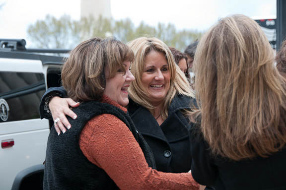 two women are hugging outside next to a building