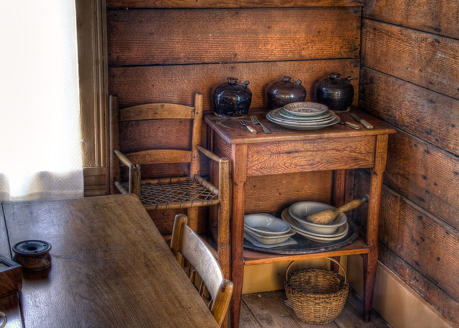 a chair, table and dishes on a table in a cabin