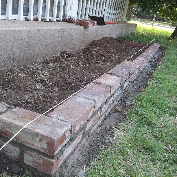 brick planter box with flower bed and grass