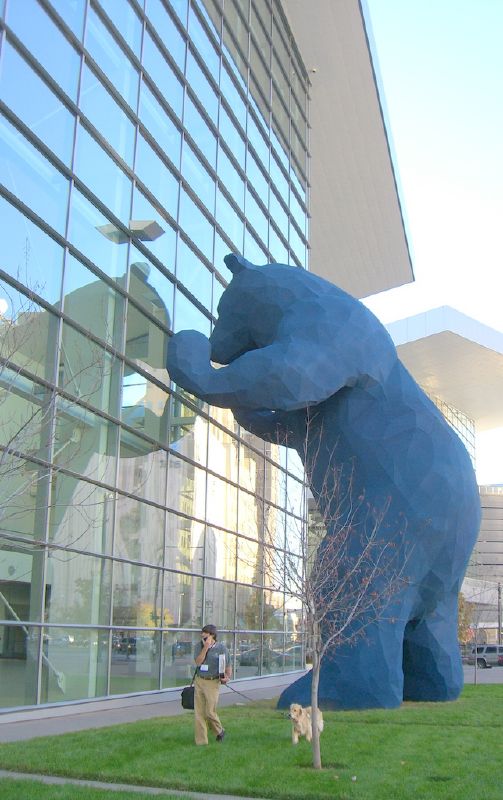a tall blue bear statue next to a building