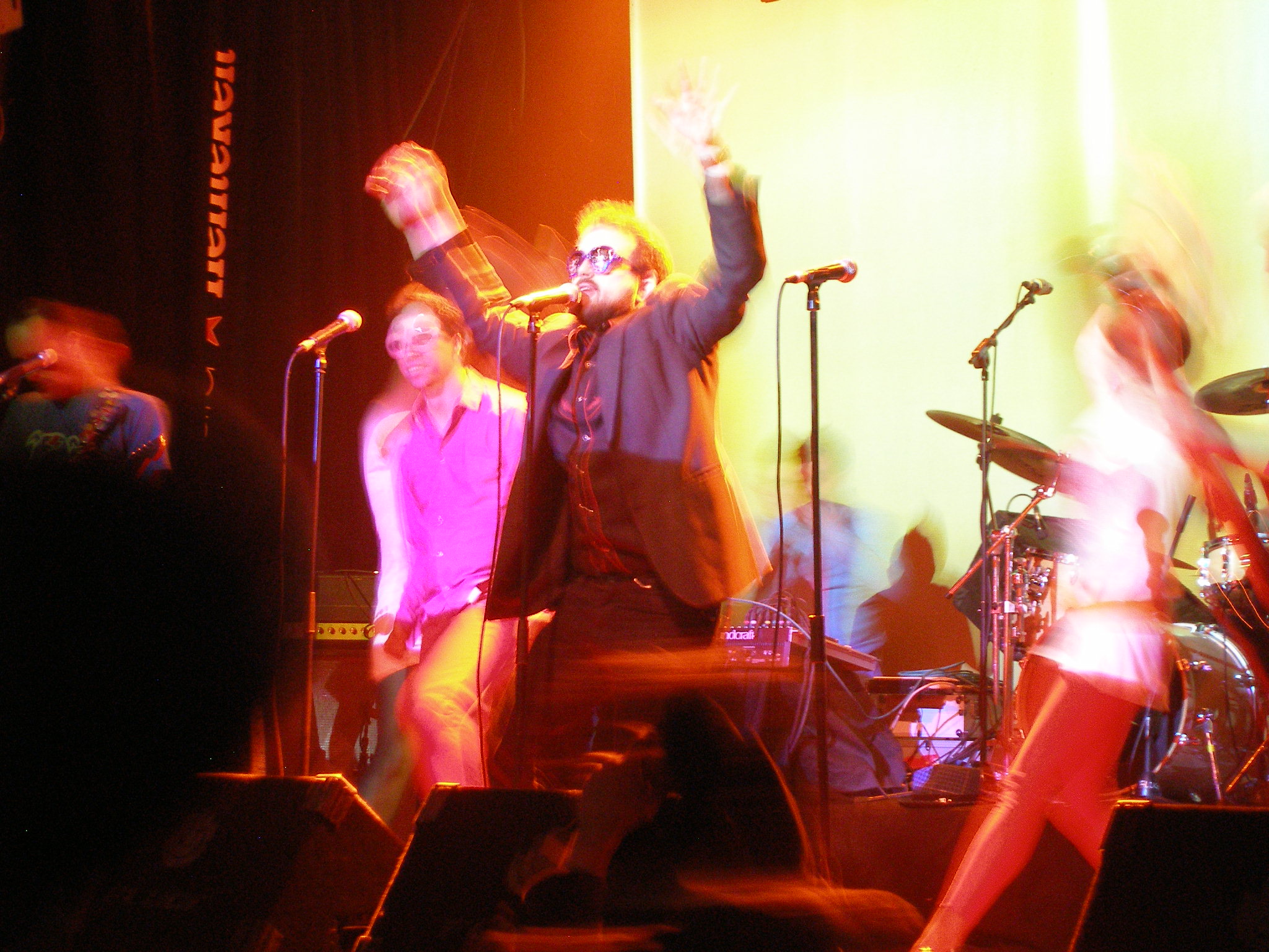 three people are on stage with arms in the air