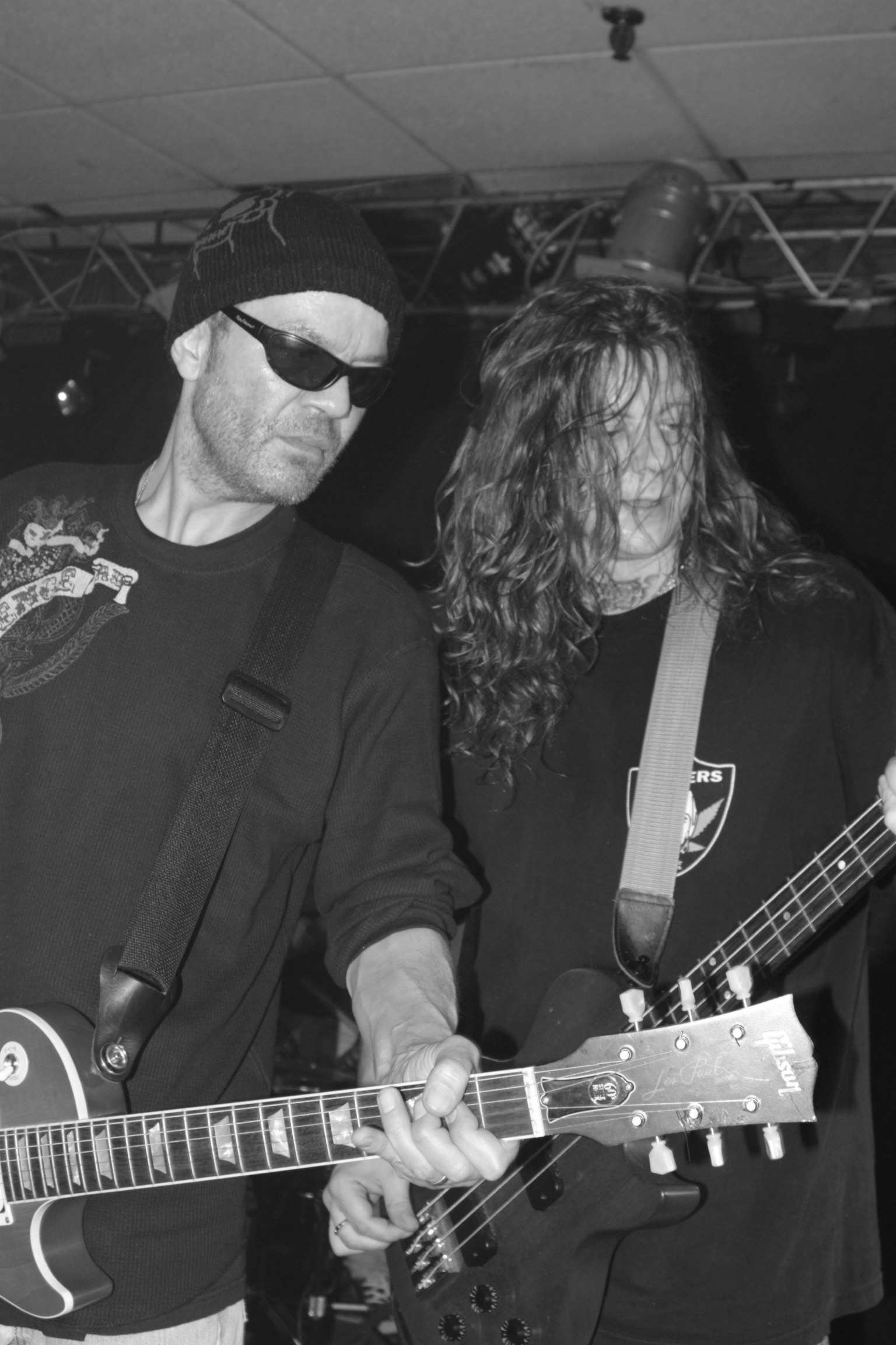 two people playing guitars on stage and one person looking at the camera