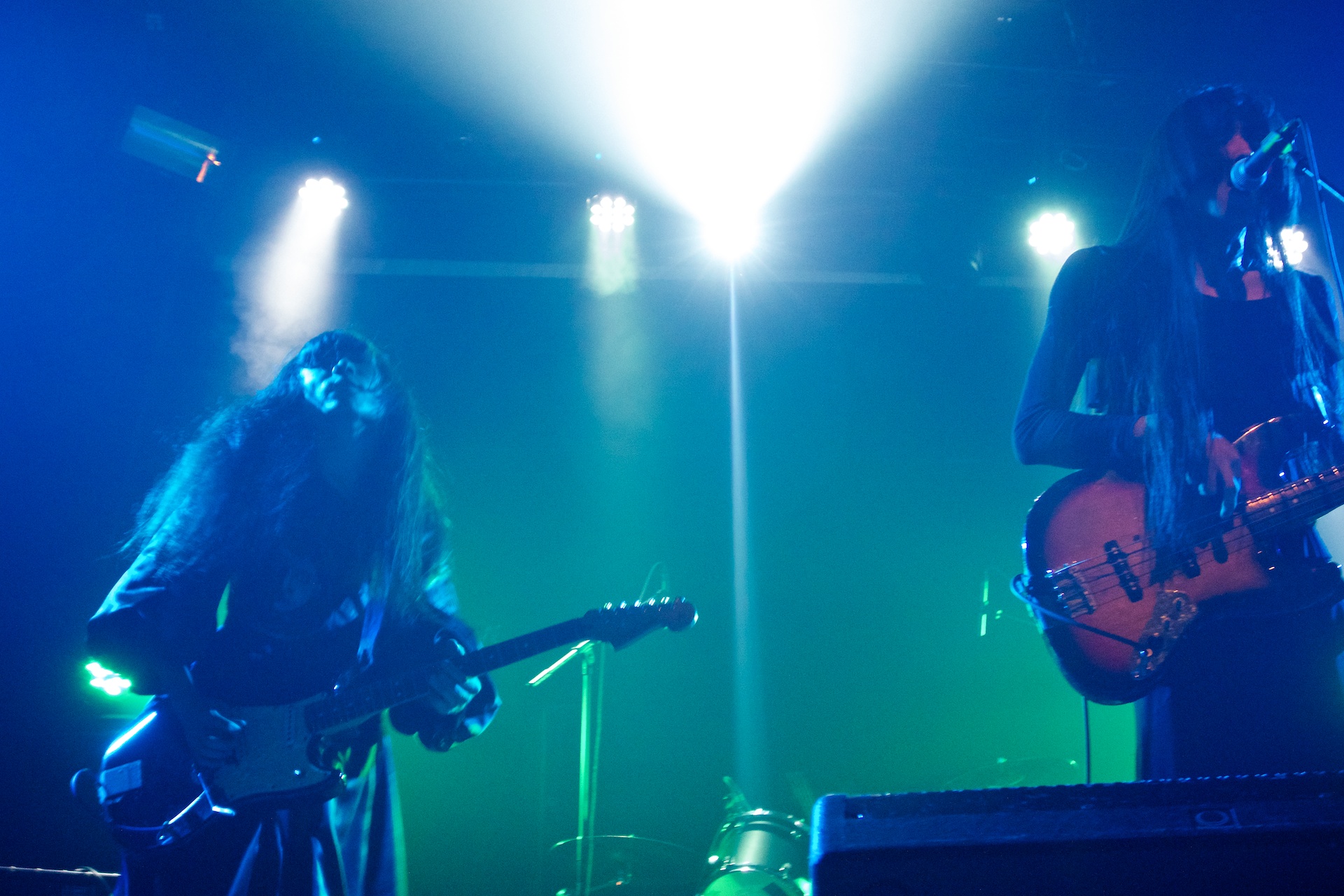 two men playing guitars on stage in front of green and blue lights