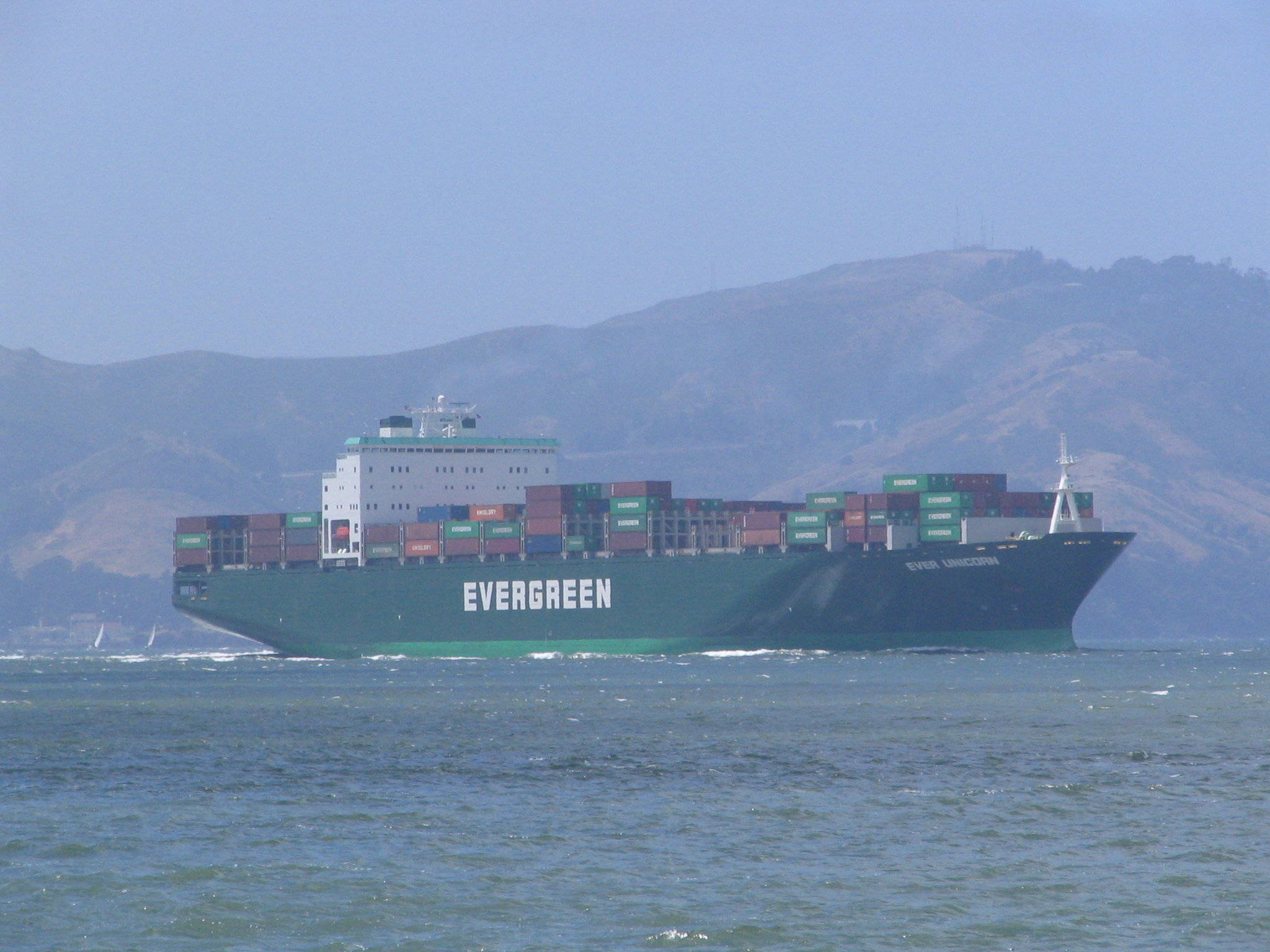 a big green ship traveling across a body of water