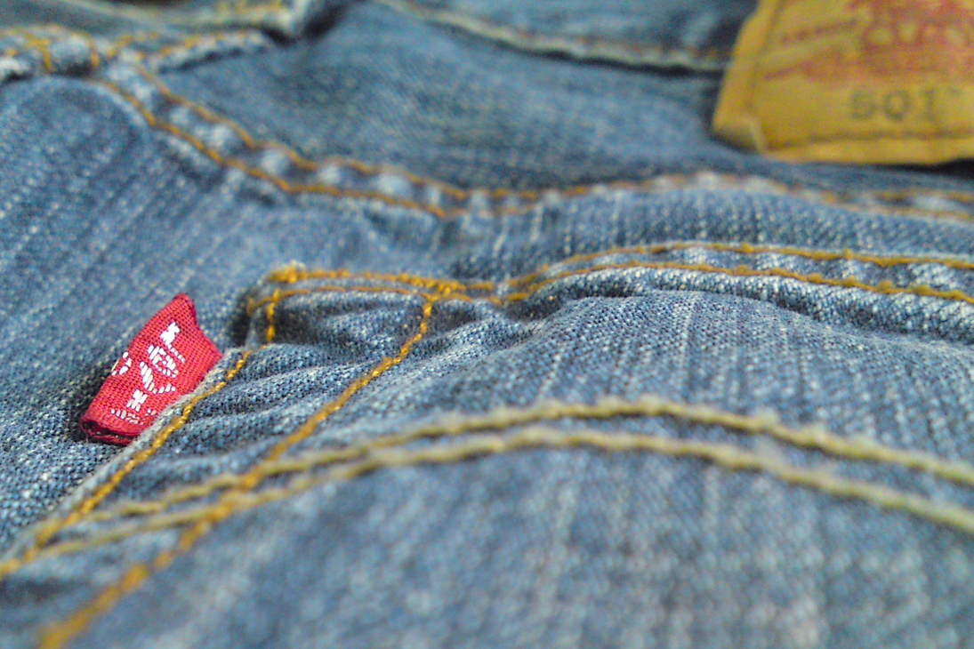 a piece of red sticker sticking out of the back of blue jean pants