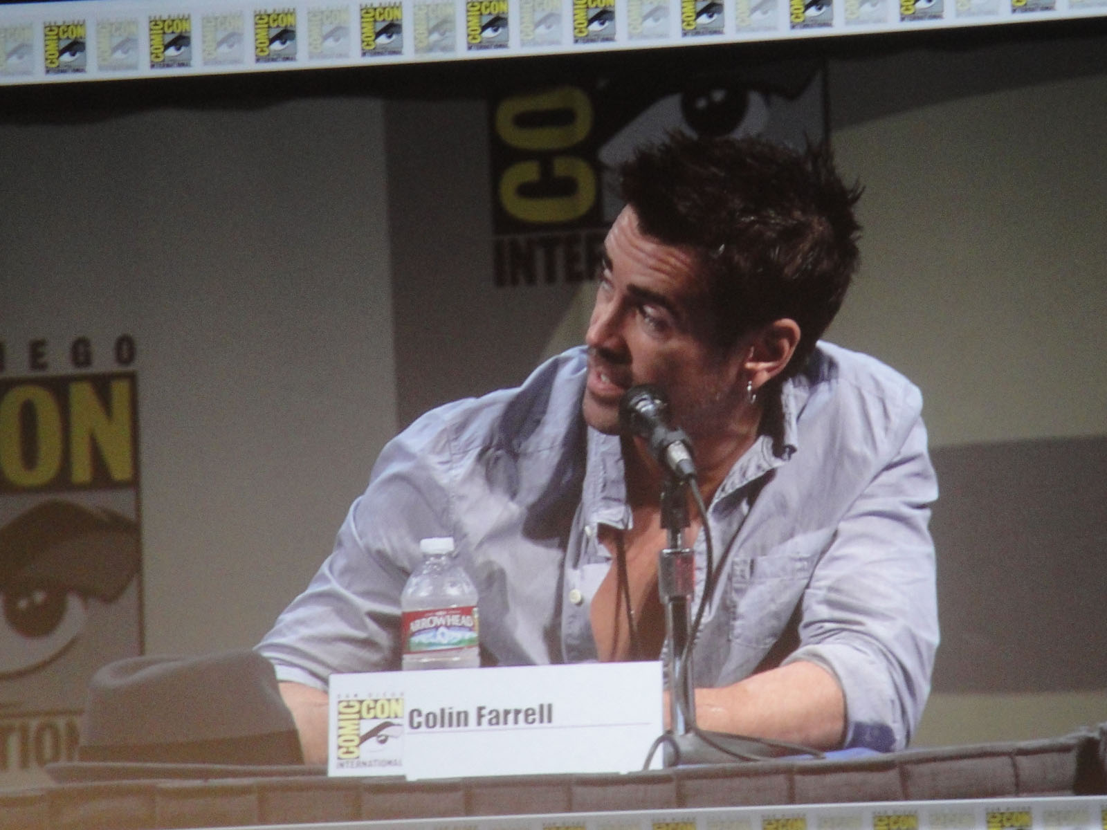 an actor sitting at a table talking on a microphone