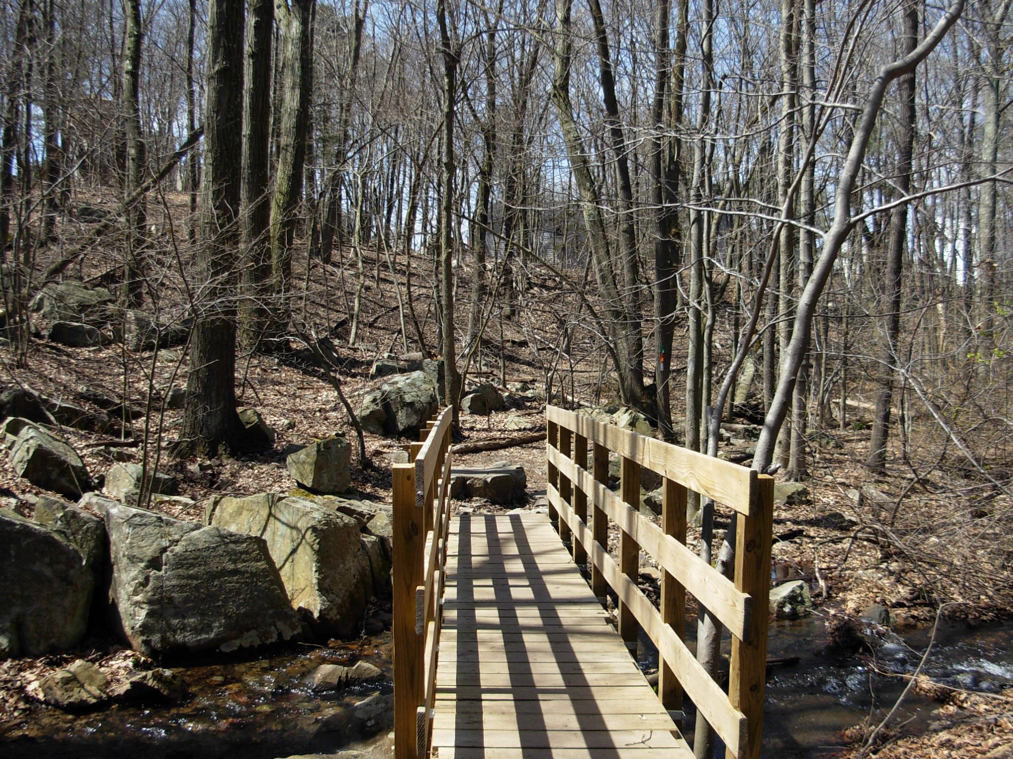 a wooden bridge surrounded by large rocks on a path