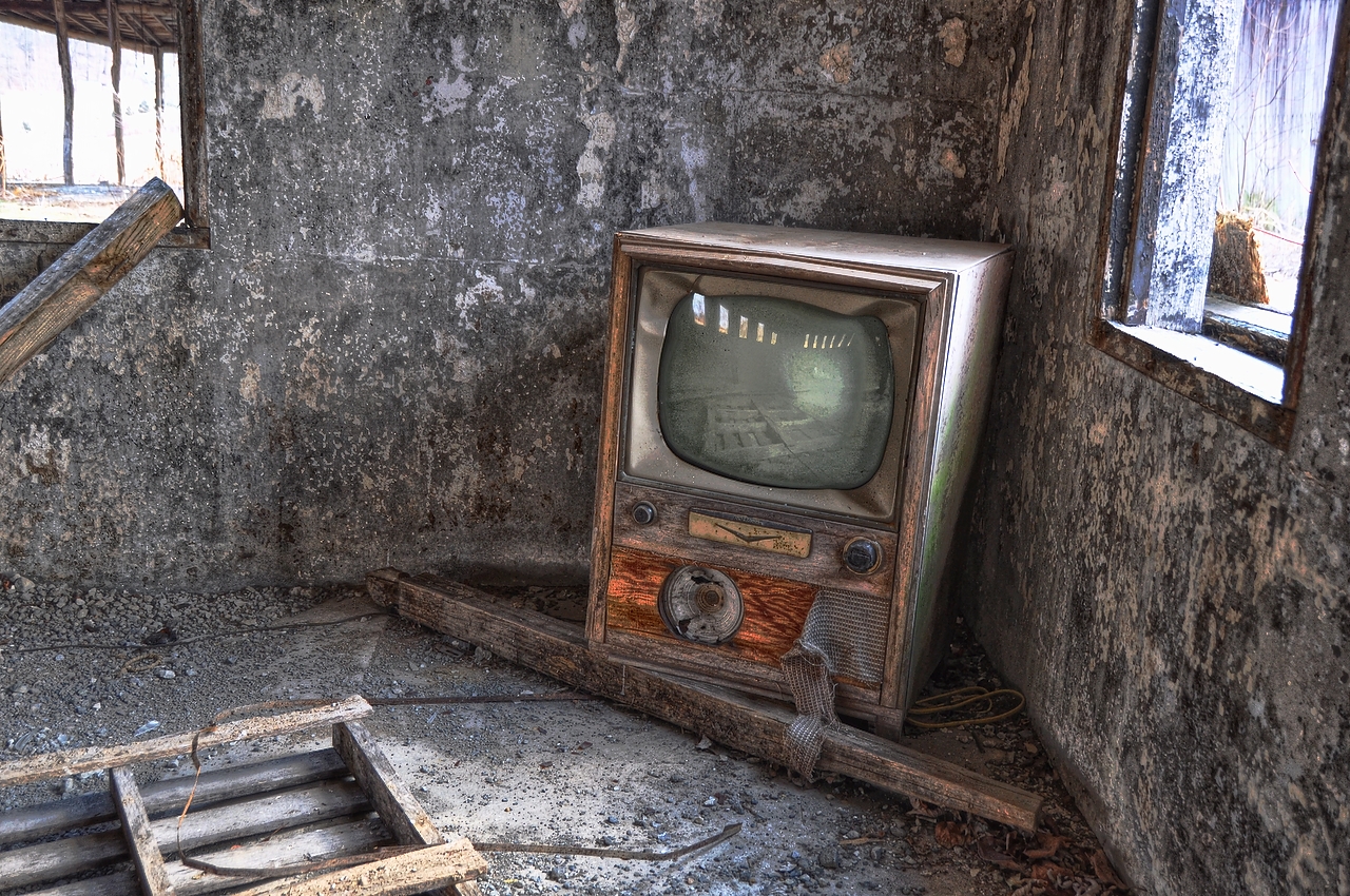an old tv in the corner of a room with a concrete wall