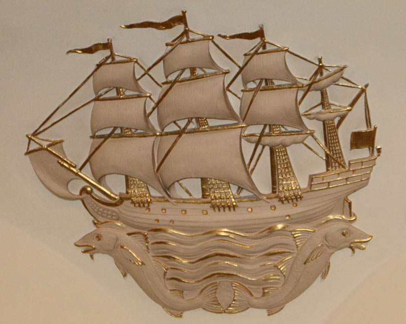 a white and gold wooden ship on the wall