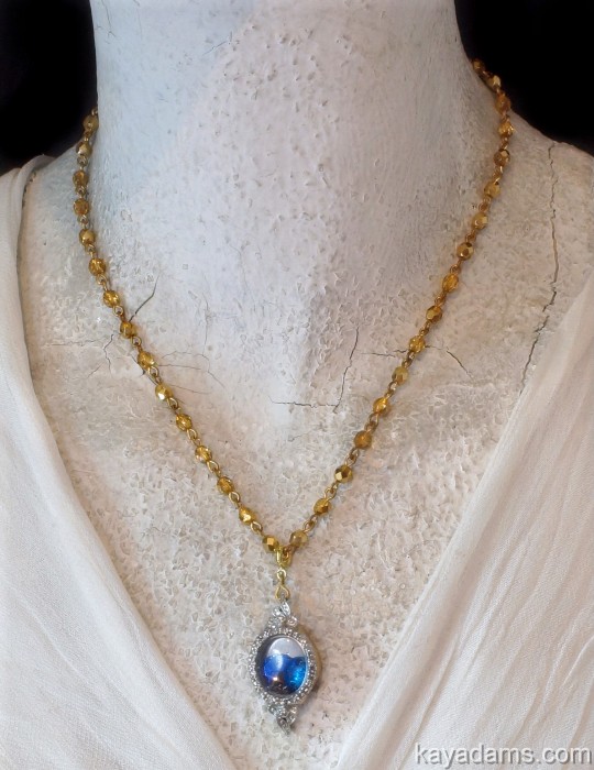 the necklace is adorned with a small beaded crystal ball and a gold plated chain