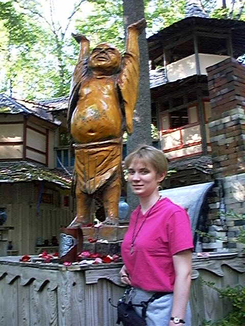 a woman standing in front of a wooden statue