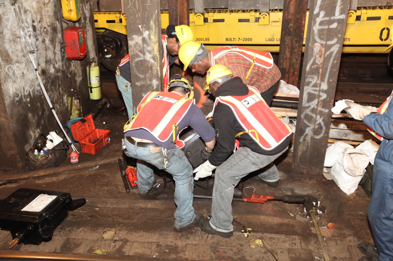 men carrying large bags under a train tunnel