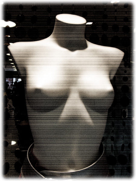a white dummy standing behind a black background