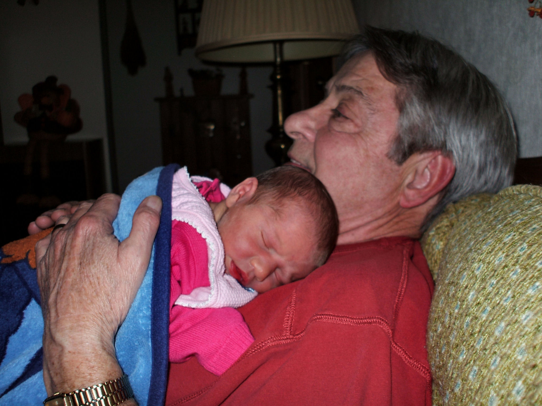 older man with gray hair holds a sleeping baby in his arms