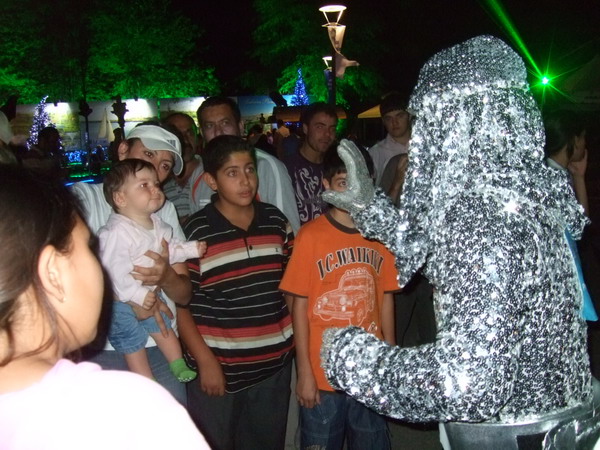 a man dressed in silver talking to many young s