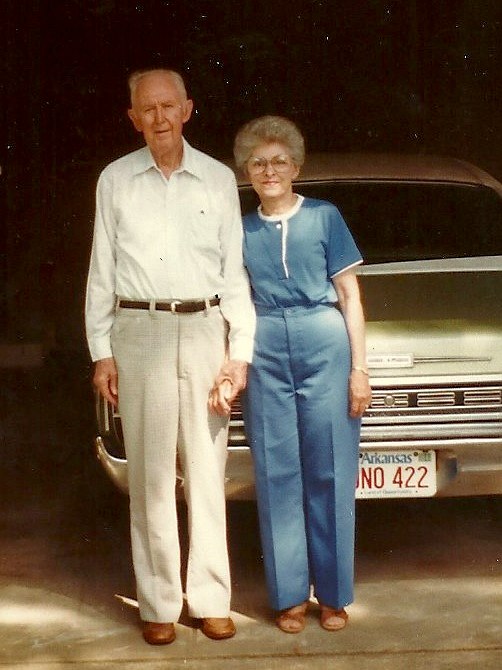 an older couple poses next to a silver car