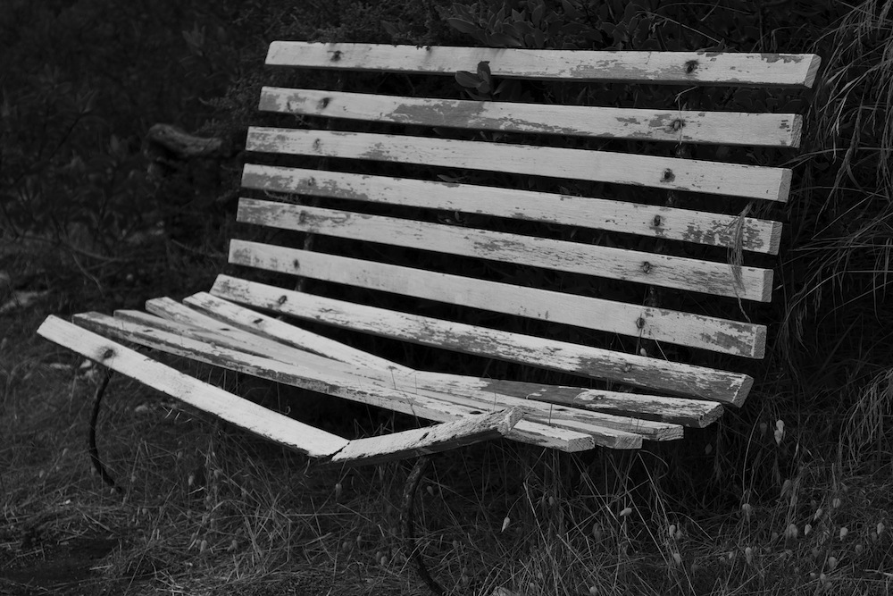 a very worn and peeling park bench in the grass