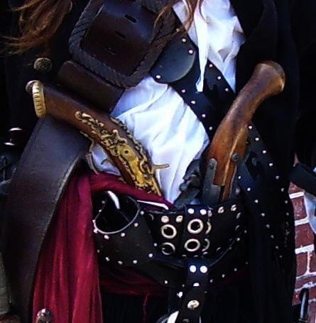 a woman in black and white shirt with a pirate outfit holding wooden instrument