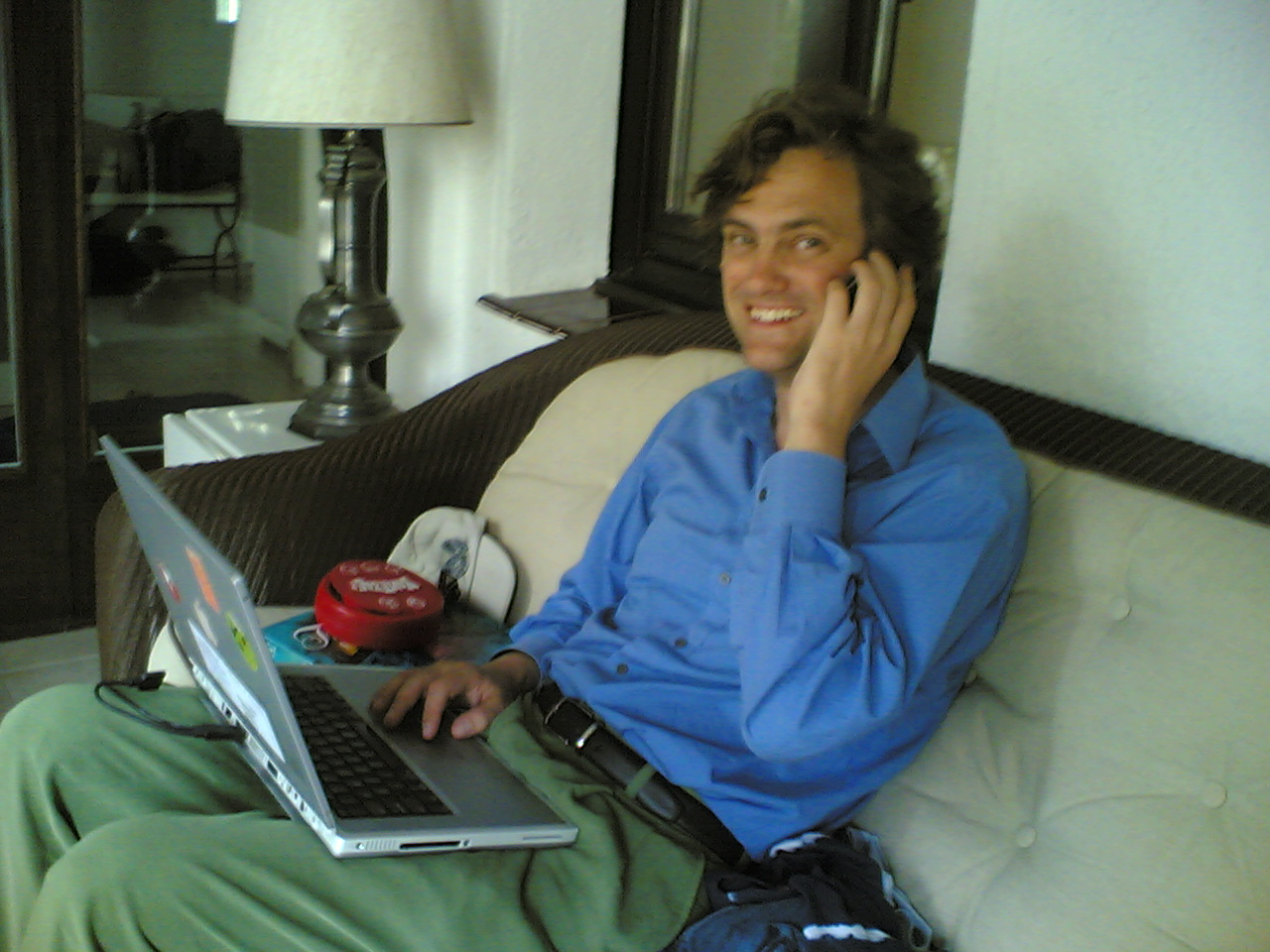 a man sitting on a couch while talking on a cell phone