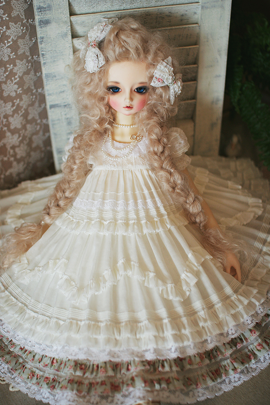 doll in a dress and wig sitting on a chair