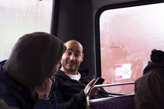two people on a bus, one is reading a phone