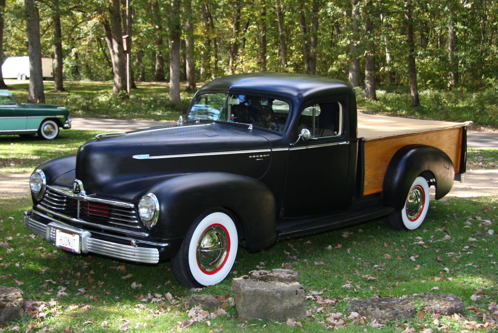 an antique truck parked in the grass near trees