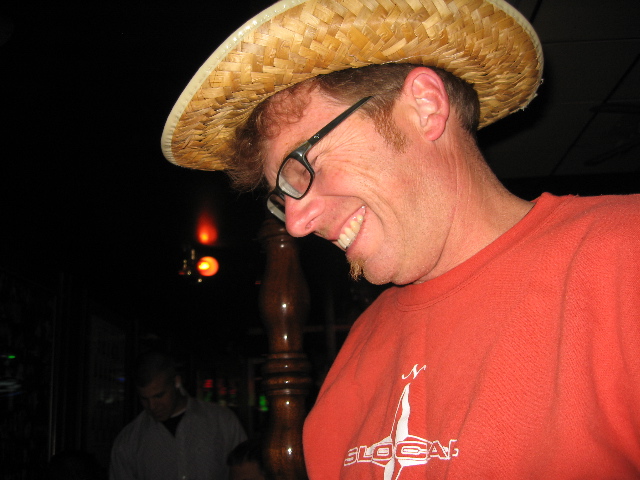 a smiling man wearing a straw hat over his eyes