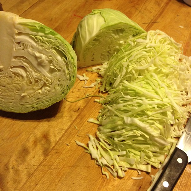 cut cabbage on a  board and next to a knife