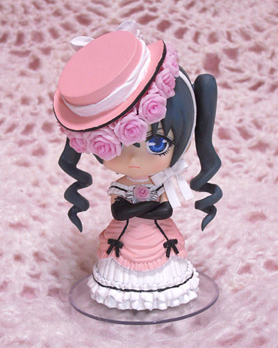 a doll figurine with a pink hat and black ribbon