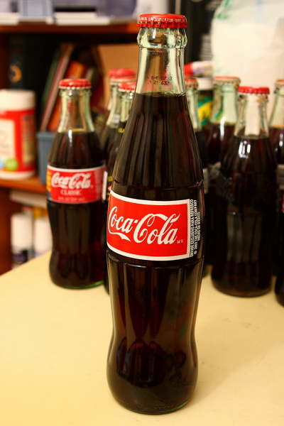 coca - cola soda is pictured in front of a selection of coke bottles
