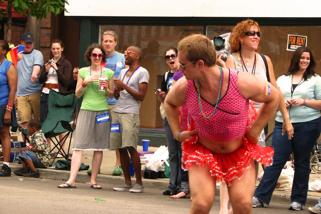 people in the street standing next to a large woman dressed in a costume