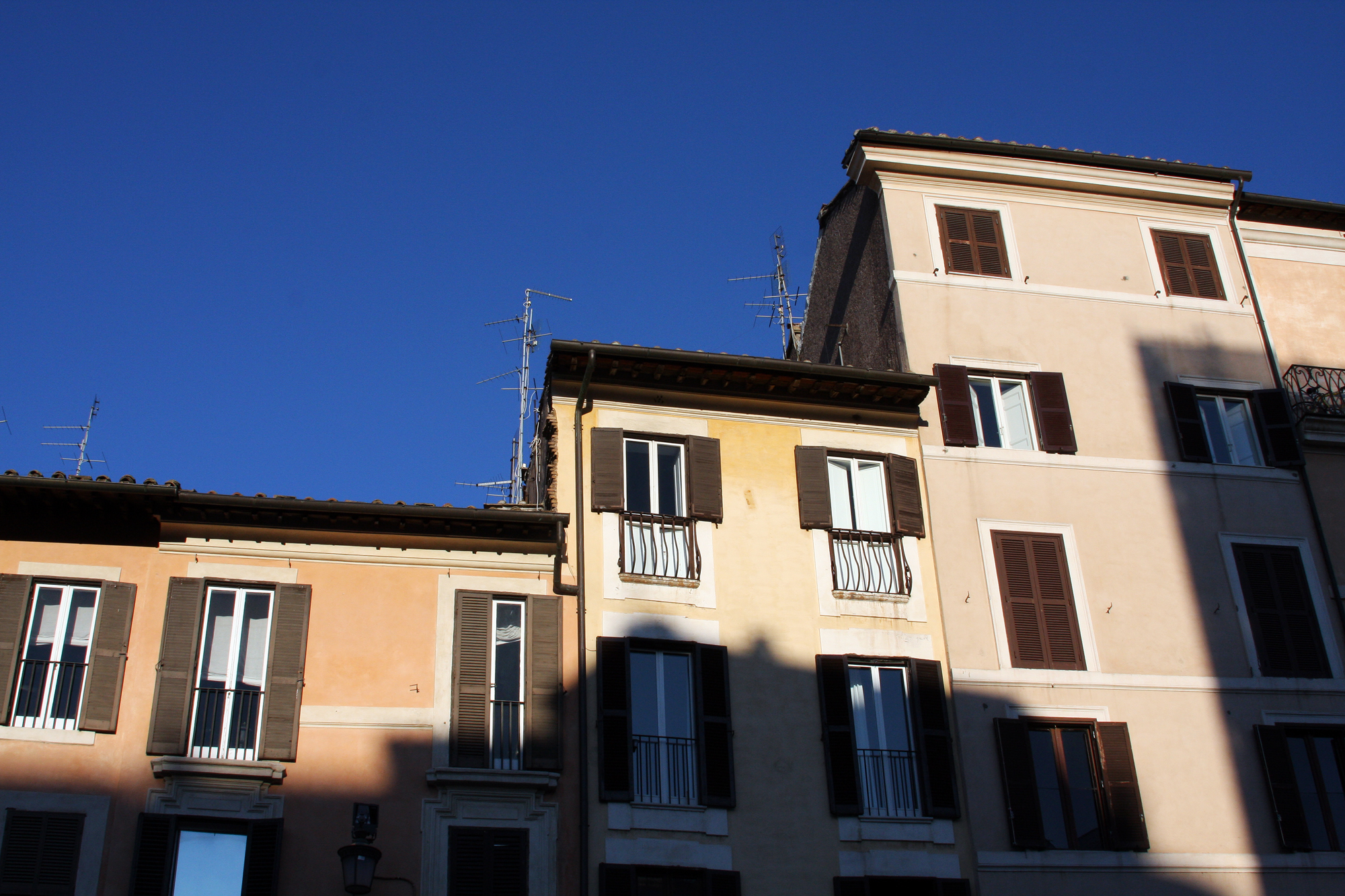 a building with brown shutters and a clear blue sky