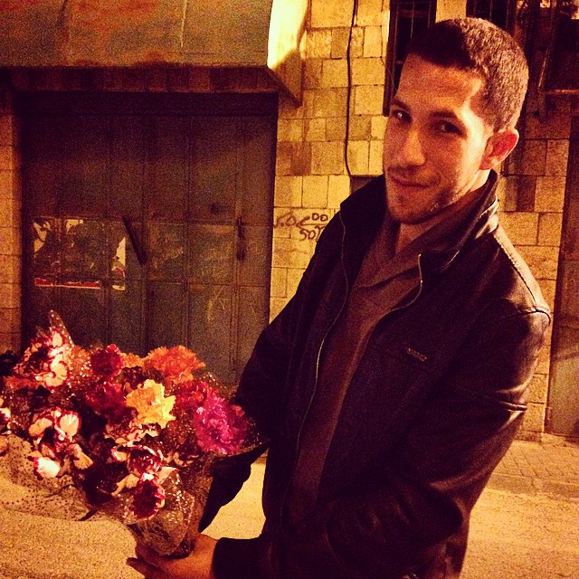 a man holding a bouquet of flowers near a fire place